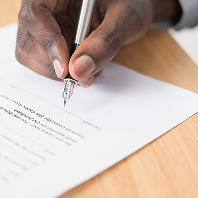 A mans hand signing a paper with a pen