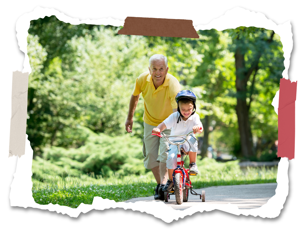 A senior citizen teaches a child how to ride a bicycle.