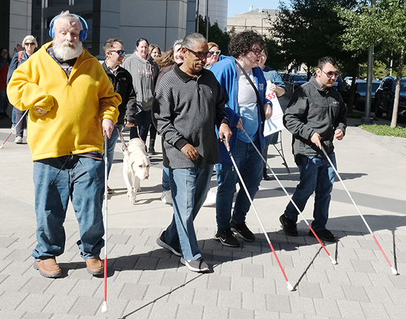 Group of people walking with white canes.