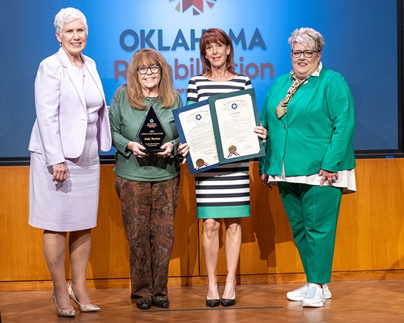 Four women on stage with one holding award