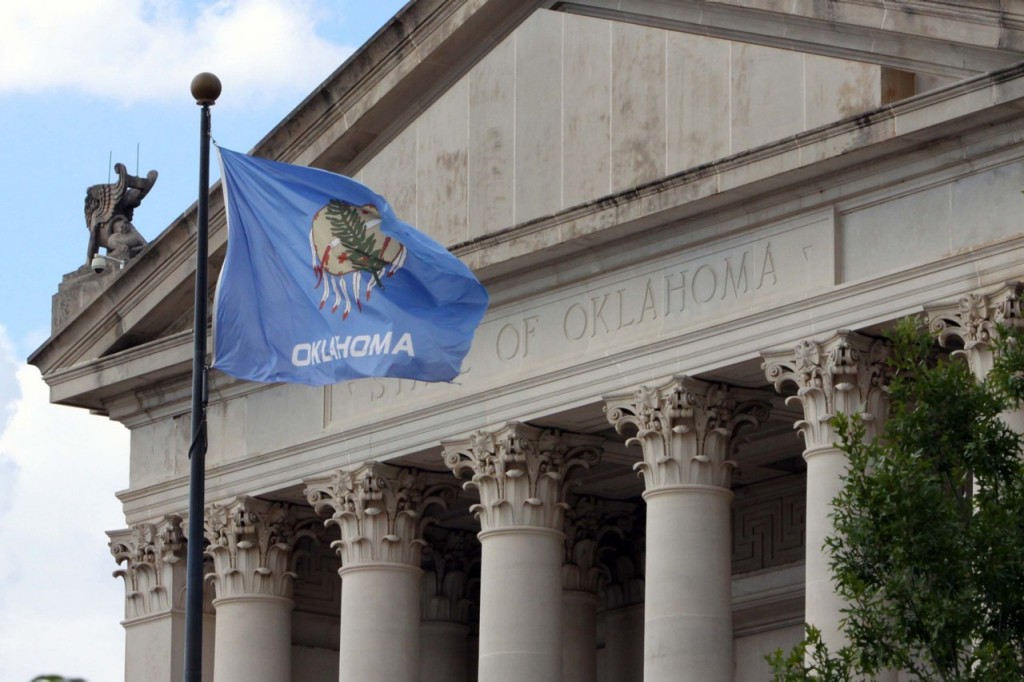 Oklahoma capital building with Oklahoma state flag in front.