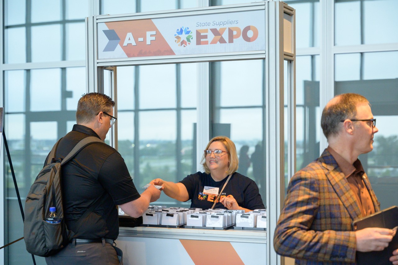 2023 Expo staff help attendee check in at kiosk.